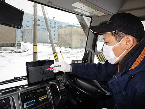 運転席のタブレットで収集しマースのアプリを使用しているごみ収集作業員の写真