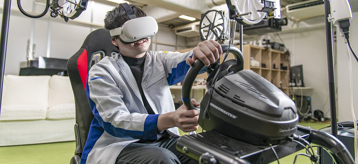 VRゴーグルを装着して走行シミュレーターを運転する若手社員